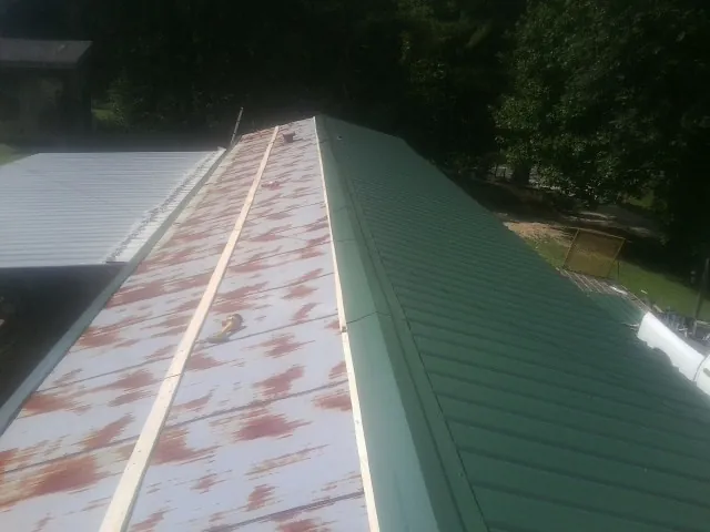 Old rusted panels beside newly installed green metal roofing — Wind Damage Roof Repair by Roofing Brothers in Blairstown