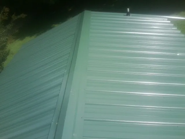 New green metal panels meeting at the ridge of a roof — Flat Roof Repair work by our crew in Blairstown