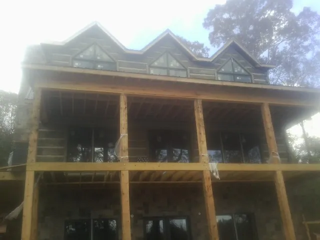 Dormers and porch framing on a large log home under construction — Roof Coating work by our crew in Blairstown