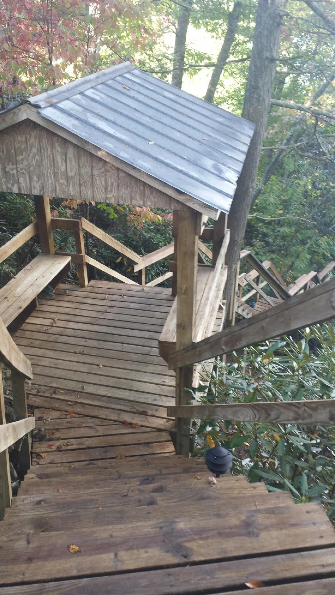 Metal roofed shelter over wooden steps on a wooded walkway — Skylight Repair & Installation work by our crew in Blairstown