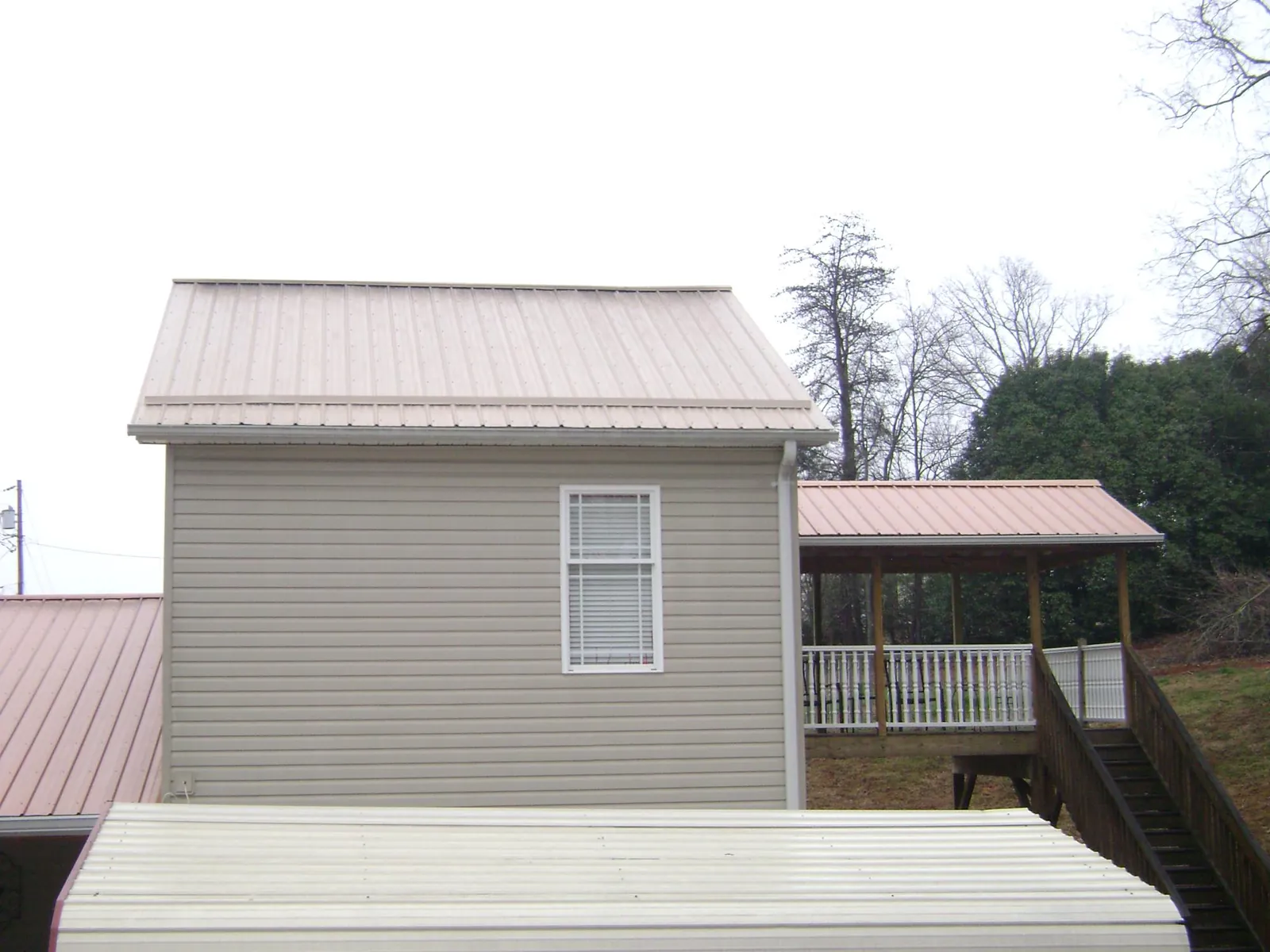 Tan metal roofs on a two story addition and attached porch, from a Roof Replacement job in Blairstown