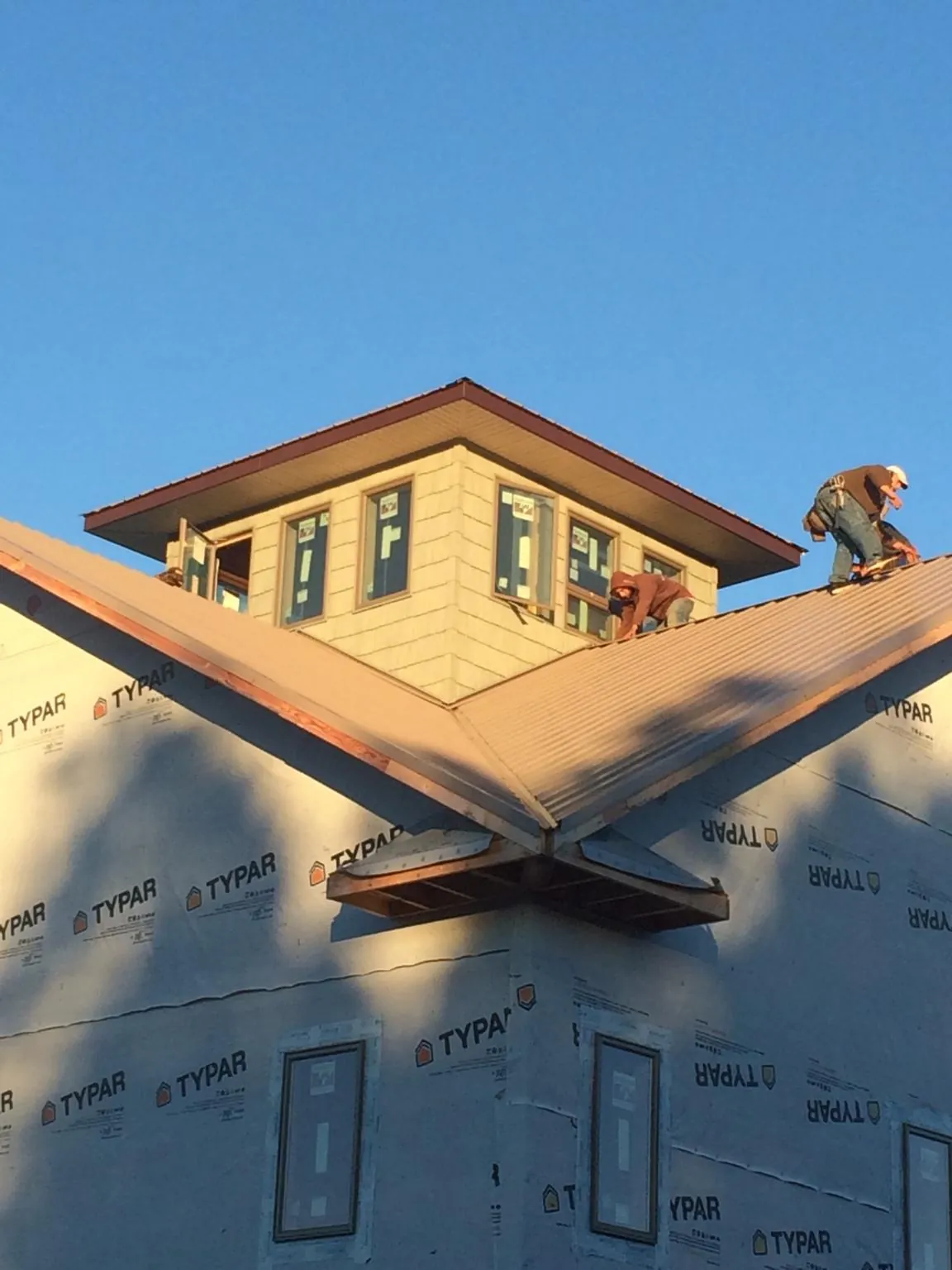 Roofers working around a rooftop cupola on a new metal roof at sunset — Roof Waterproofing in Blairstown by Roofing Brothers